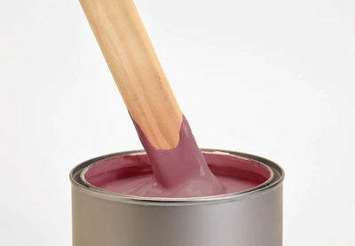 Image of a pot containing dark red mylands wall primer with a brush inside