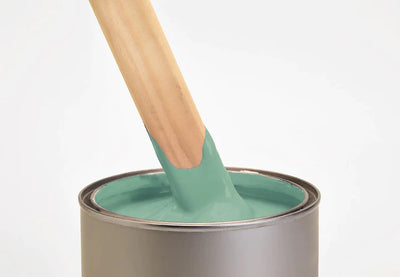 Image of a pot containing myhlands green wall primer with a brush inside